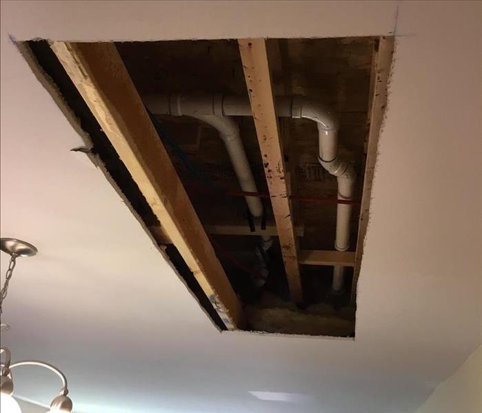 Ceiling drywall cut away to treat joists and plumbing