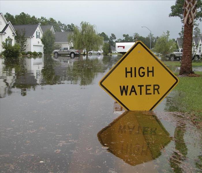 high water sign by flooded houses