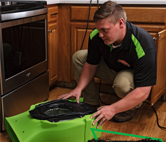 servpro tech placing air mover in kitchen