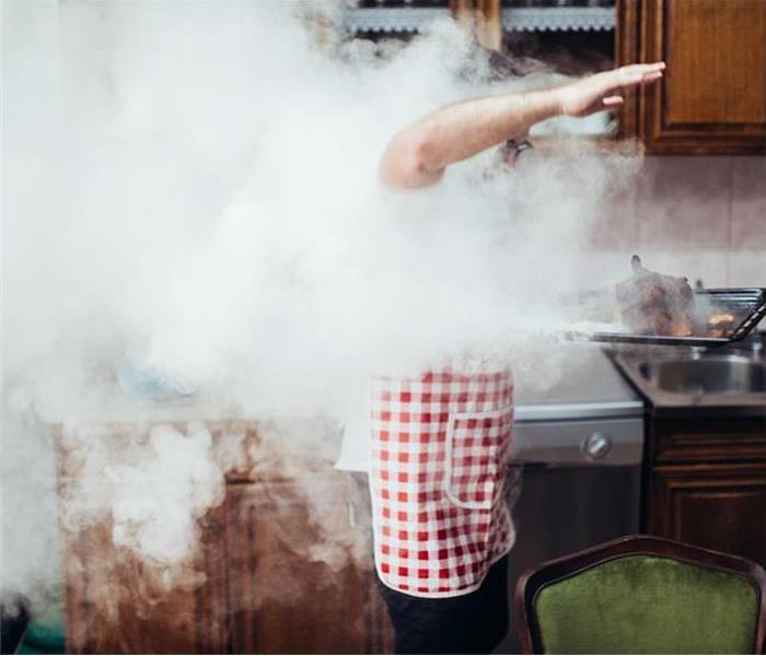 Man in smoky kitchen holding burning food