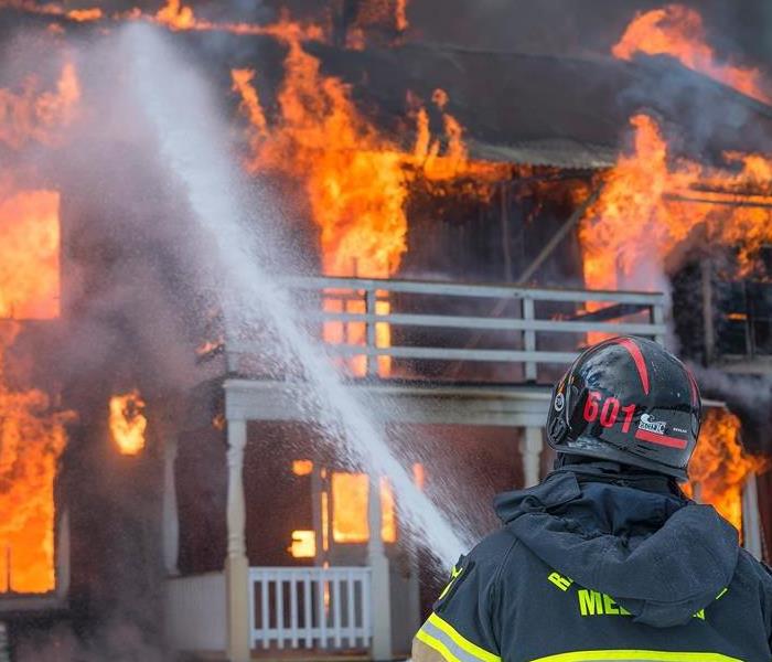 Photo showing house engulfed in flames with fireman attempting to put out